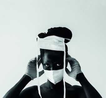 Black and white photo of the artist wearing bandages on their face