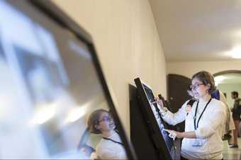 Female volunteer guide operates one of the digital screens in Tate Britain