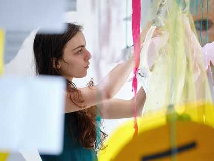 Young person hangs mixed media in an art installation at Tate St Ives