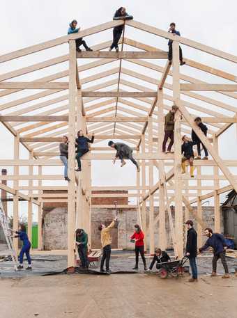 The artist collective Assemble sit and stand by a shed