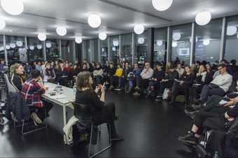 Three speakers address a seated audience