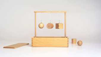Aurélien Froment's Second Gift. A wooden structure with three hanging wooden circles and shapes