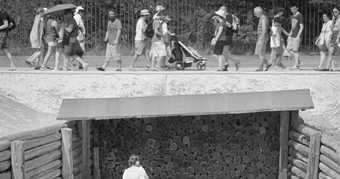 Black and white photograph of people walking above a pit