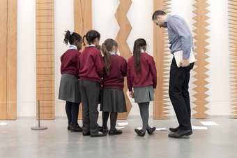A group of children looking at an artwork with a teacher