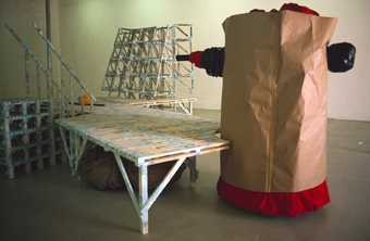 A photograph of a Phyllida Barlow installation at the Diorama Gallery including wood and a large sculpture made of brown paper
