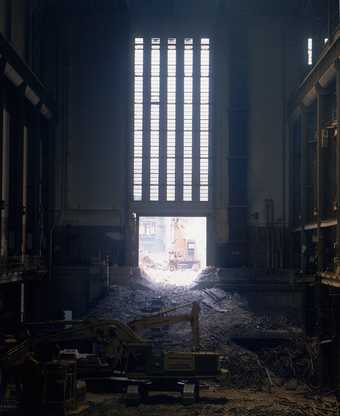 Interior view of Bankside Power Station after plant removal, showing rubble and digger in the foreground 1995