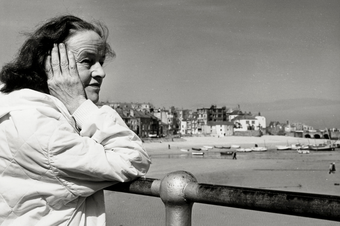 Barbara Hepworth stands in front of a view of St Ives harbour