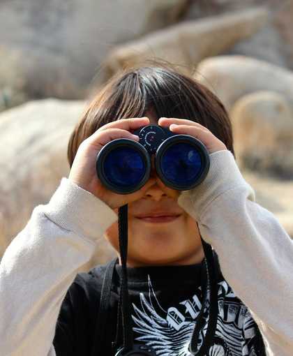 photograph of a child looking through binoculars