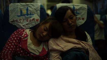 a girl falls asleep on a woman's shoulder in an airport