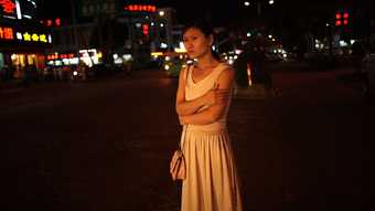 a young woman stands in the street at nighttime