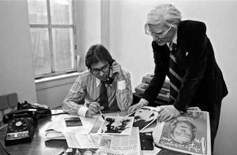 Black and white photograph of Bob Colacello and Andy Warhol in the offices of Interview magazine