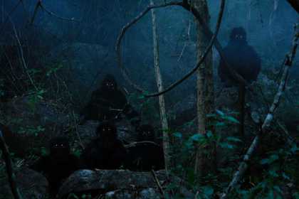 Misty dark film still of two people wearing black hooded clothing with lights for eyes in a woodland scene