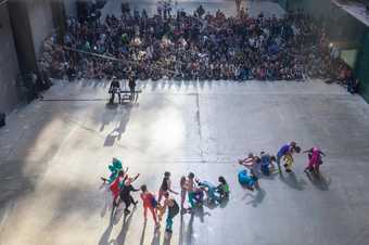 Chain of dancers in bright leotards being watched by a crowd