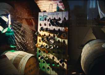 Film still of wine bottles in a cellar