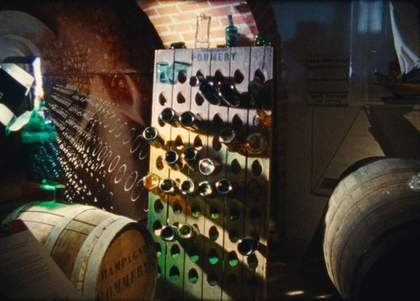 Film still of wine bottles in a cellar
