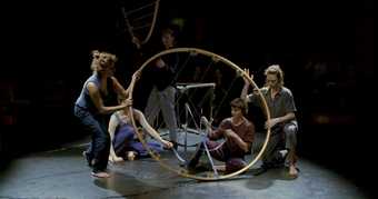 people hold a wooden hoop in a dark space