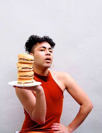 Travis Alabanza poses with a tray of burgers