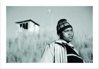 Black and white photo of a person standing against long grass