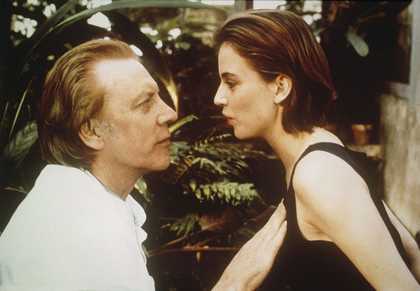 A couple look at each other and start to embrace in front of a green tree