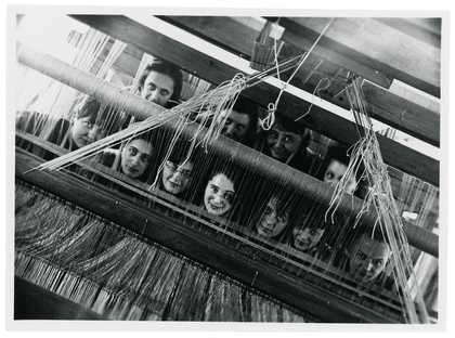 A group of Bauhaus weavers looking through the loom in to the camera