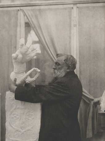 Rodin placing the plaster Clenched Hand with Imploring Figure on a pedestal, in the Pavillon de l’Alma, Meudon 1906. Photo by unknown photographer, Musée Rodin