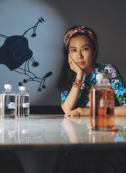 Anicka sits at a table surrounded by bottles