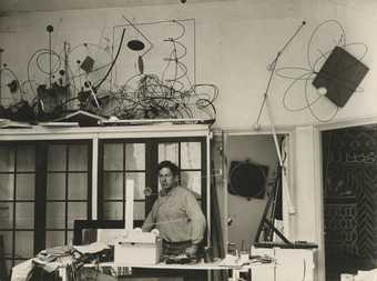A black and white photograph of Calder in his Parisian studio