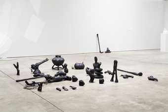 Camille Henrot Objets Augmentés 2012, a series of organic shaped tar covered clay sculptures on a floor