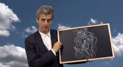 Peter Capaldi holds a chalkboard