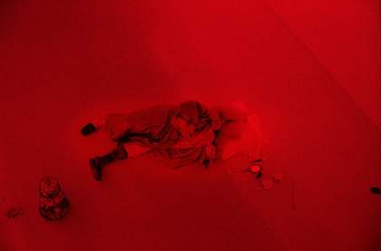 A performer playing the role of Louis XIV in a red-hued gallery