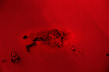 A performer playing the role of Louis XIV in a red-hued gallery