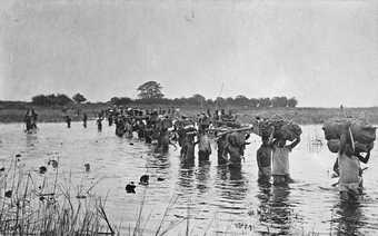 Carriers transporting stores across the Chambeshi River in Zambia, Southern Africa, as part of the Tanganyika Expeditionary Force during the First World War