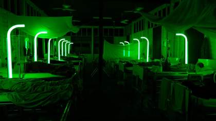 A series of green vertical curved lights stand up in a hospital room