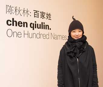 Artist Chen Qiulin stands in front of the exhibition entrance for Chen Qiulin: One Hundred Names at the Shepparton Art Museum, Australia (4 June – 24 July 2016)