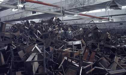 a huge pile of abandoned wooden desks and chairs, all broken on top of each other.
