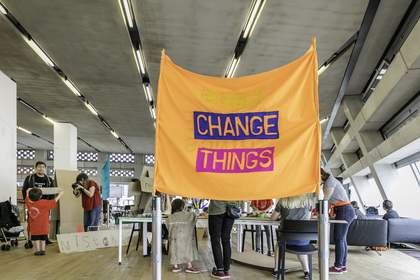 A large orange banner with the words ‘change things’ written on it