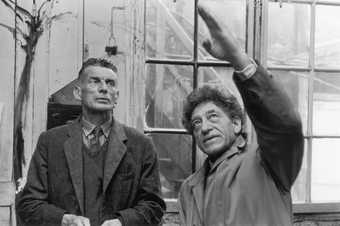 A black and white photograph of Samuel Beckett and Alberto Giacometti in Giacometti's studio