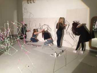 A photograph of students creating work on the walls of a gallery space