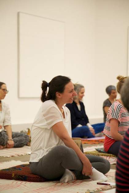 Close up on a visitor sitting on a yoga mat in the gallery