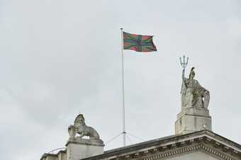 A black, green and red version of the union jack flag flying above Tate Britain 