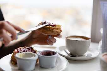 close up of a person spreading jam on a scone