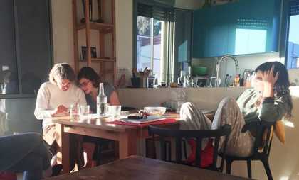 Three women sitting in a kitchen around a wooden table