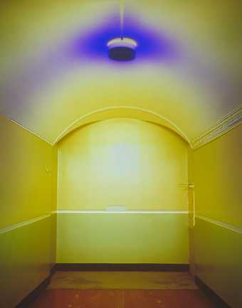 Photograph of a yellow painted corridor with a blue ceiling light