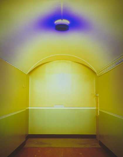 Photograph of a yellow painted corridor with a blue ceiling light