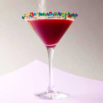 a red cocktail in a martini glass with coloured dots around the rim