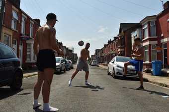  A group of young people playing football in the middle of a road 