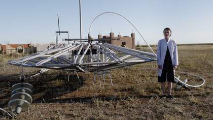 Vidokle film still of someone standing in a barren field with a large sculpture