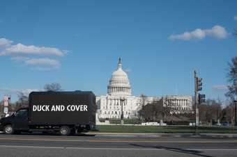 A truck parked in front of the US Capitol building with the words 'Duck and Cover' on an LED screen