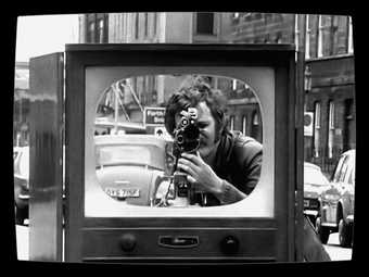 Black and White image of man holding a camera and filming