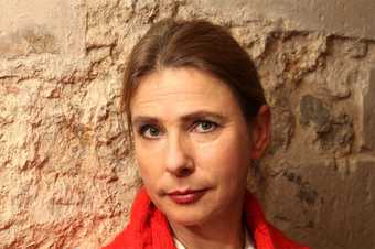 Photograph of Lionel Shriver portrait picture of her staring at the camera wearing red